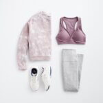 Stitch Fix women’s hiking outfit with purple sports bra, purple and white printed pullover, grey leggings and white sneakers.