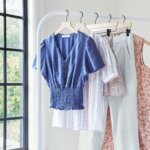 Stitch Fix women’s coastal grandmother style tops, bottoms and dresses in blue, white, light pink and tan hanging on a rack.