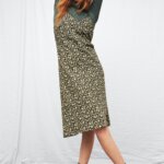 Stitch Fix model wearing women's 90s fashion outfit with olive turtleneck top, black floral midi slip dress, black combat boots.