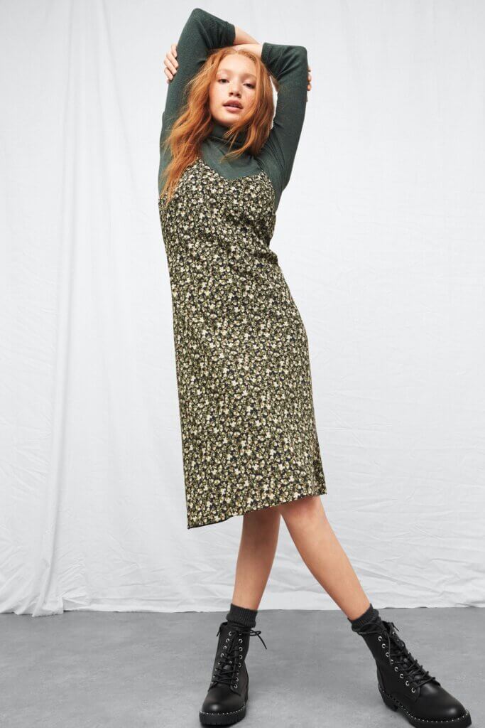 Stitch Fix model wearing women's 90s fashion outfit with olive turtleneck top, black floral midi slip dress, black combat boots.
