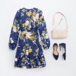 Stitch Fix women’s white and yellow floral accessorized navy blue dress for a wedding with off-white purse and navy shoe.