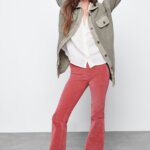 Stitch Fix model wearing women’s Y2K fashion outfit with white shirt, olive shacket, pink flared pants and platform sneakers.