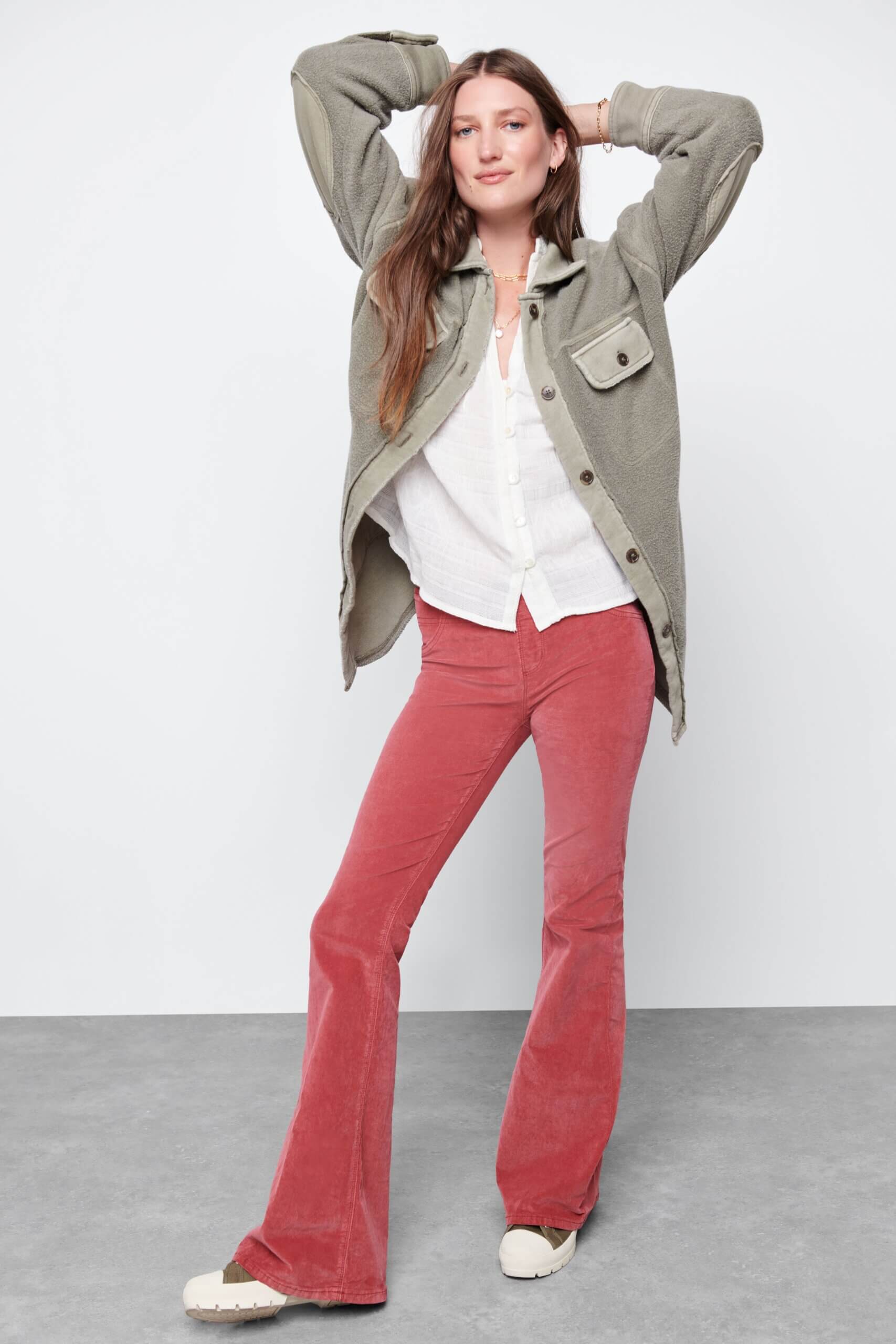 Stitch Fix model wearing women’s Y2K fashion outfit with white shirt, olive shacket, pink flared pants and platform sneakers.