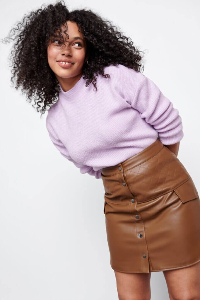 Stitch Fix model wearing brown faux leather button-up mini skirt outfit with a lavender sweater.
