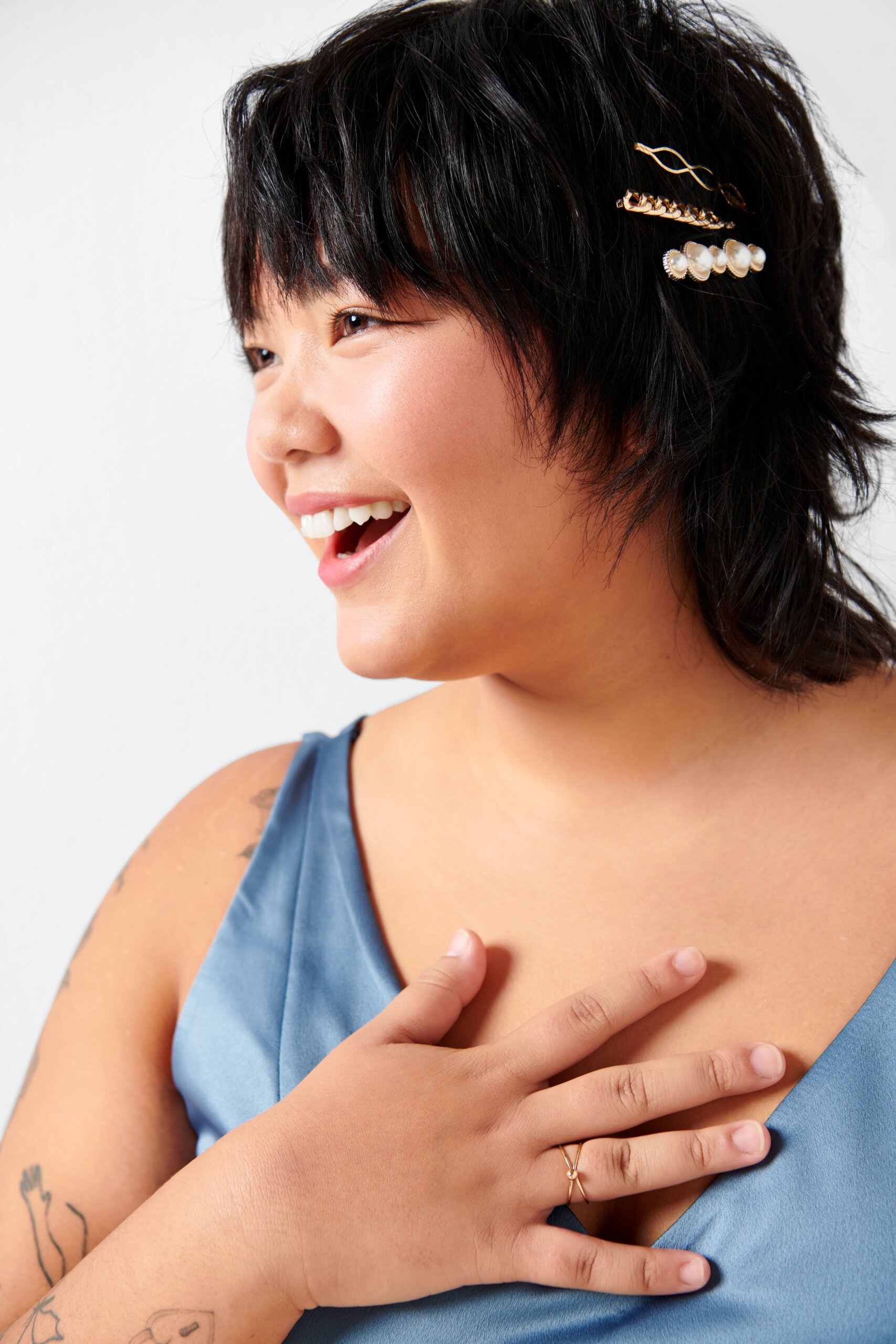 Stitch Fix model wearing a blue dress with a gold ring and gold hair clip accessories.