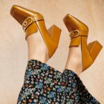 Stitch Fix women’s model wearing brown block-heel loafers and black wide-leg pants with multi-color print.