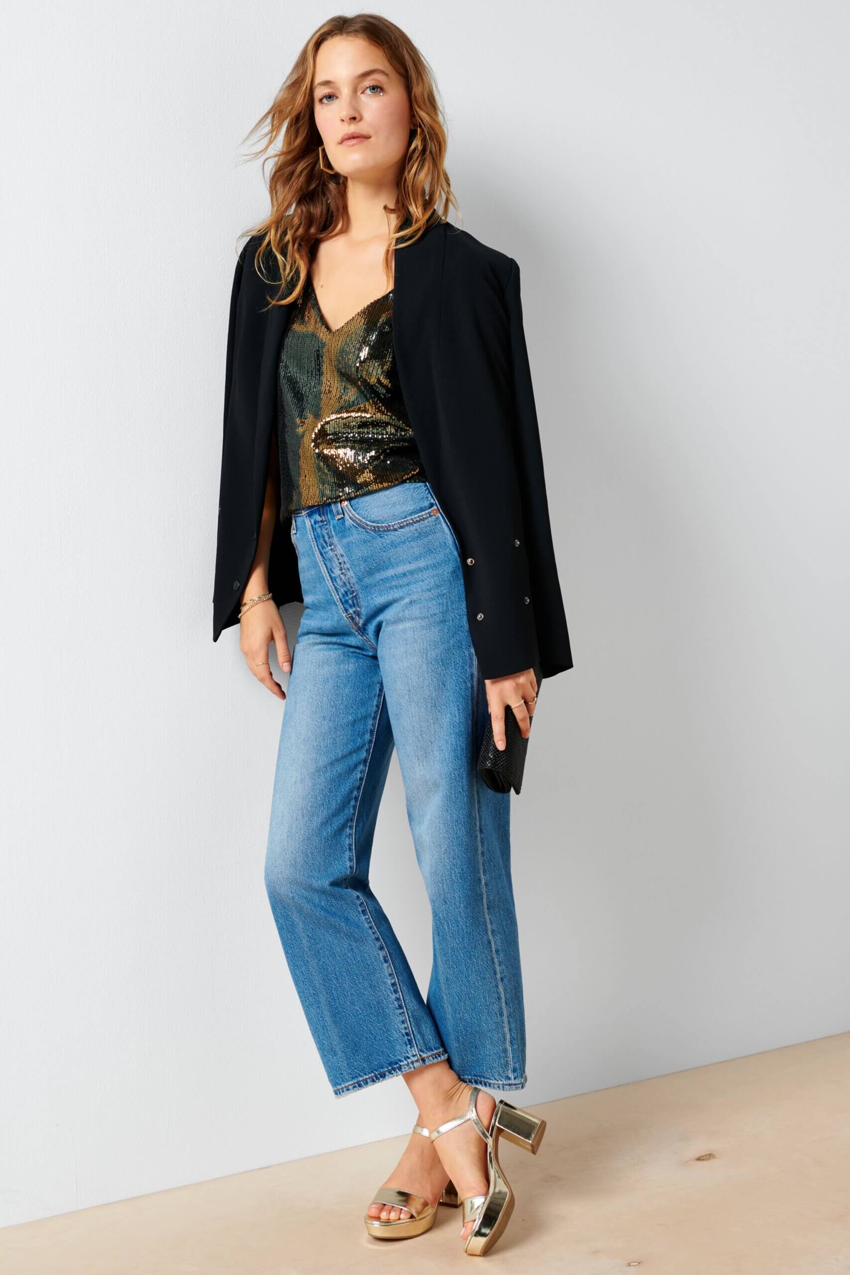 Stitch Fix women’s model wearing a black blazer, sequin blouse, wide-leg jeans and silver heels.