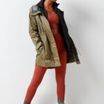 Stitch Fix model wearing women’s hiking outfit with burnt orange sports bra and leggings, hooded parka, socks and printed boots.