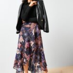 Stitch Fix model wearing printed wrap-over skirt outfit with a black crew neck sweater, black leather blazer and tan pumps.