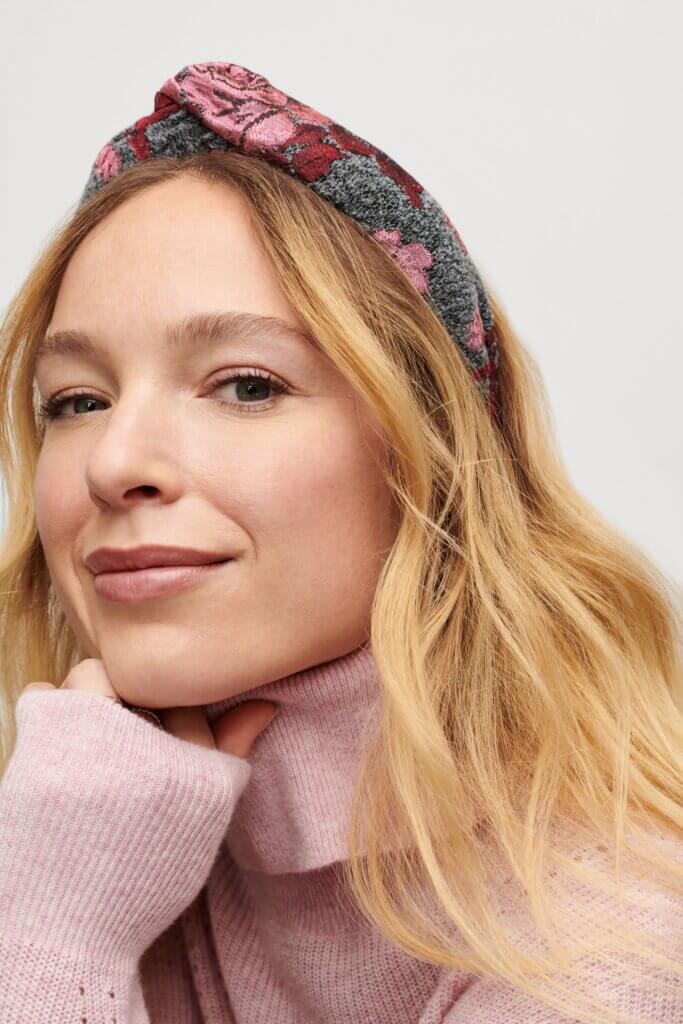 Stitch Fix model wearing women's regencycore outfit featuring floral knotted headband and pink turtleneck sweater.
