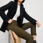 Stitch Fix women’s model wearing modern business formal outfit with olive pants, white shirt, black blazer and black booties.