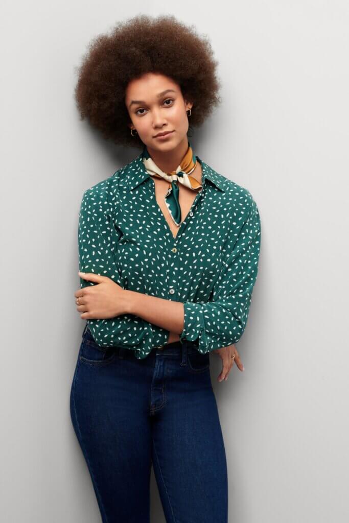 Stitch Fix model in French style outfit of teal printed button down, blue denim and a neck scarf.