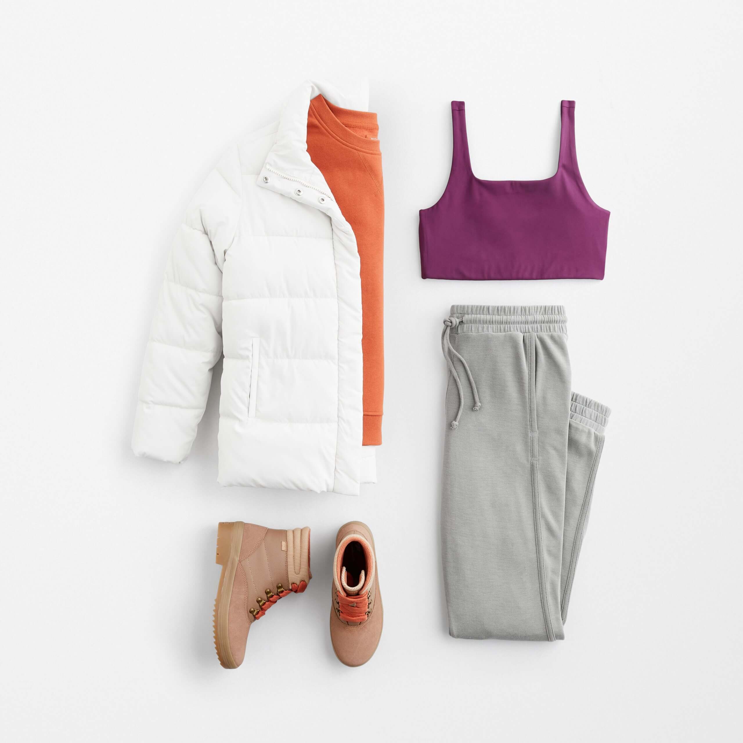 Stitch Fix women’s outfit for what to wear hiking with sports bra, orange top, white puffer jacket, joggers and hiking boots.