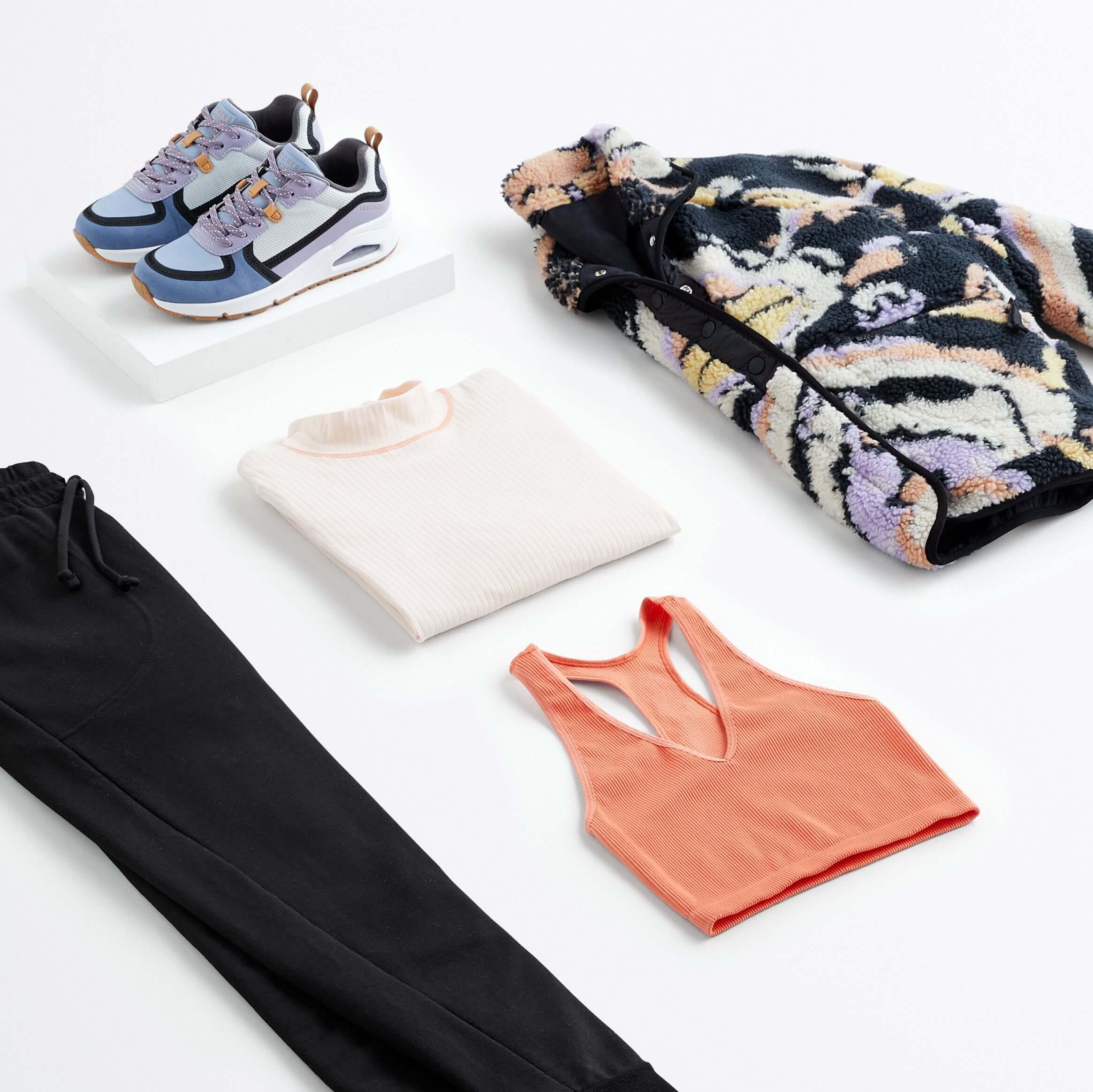 Stitch Fix women’s what to wear hiking outfit with black joggers, coral sports bra, white long-sleeve shirt, sneakers and graphic fleece jacket.