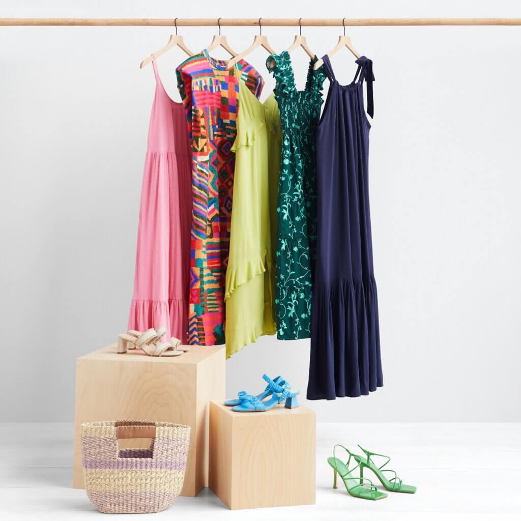 Stitch Fix women’s clothing rack with colorful dresses with heeled sandals and woven bag accessories.