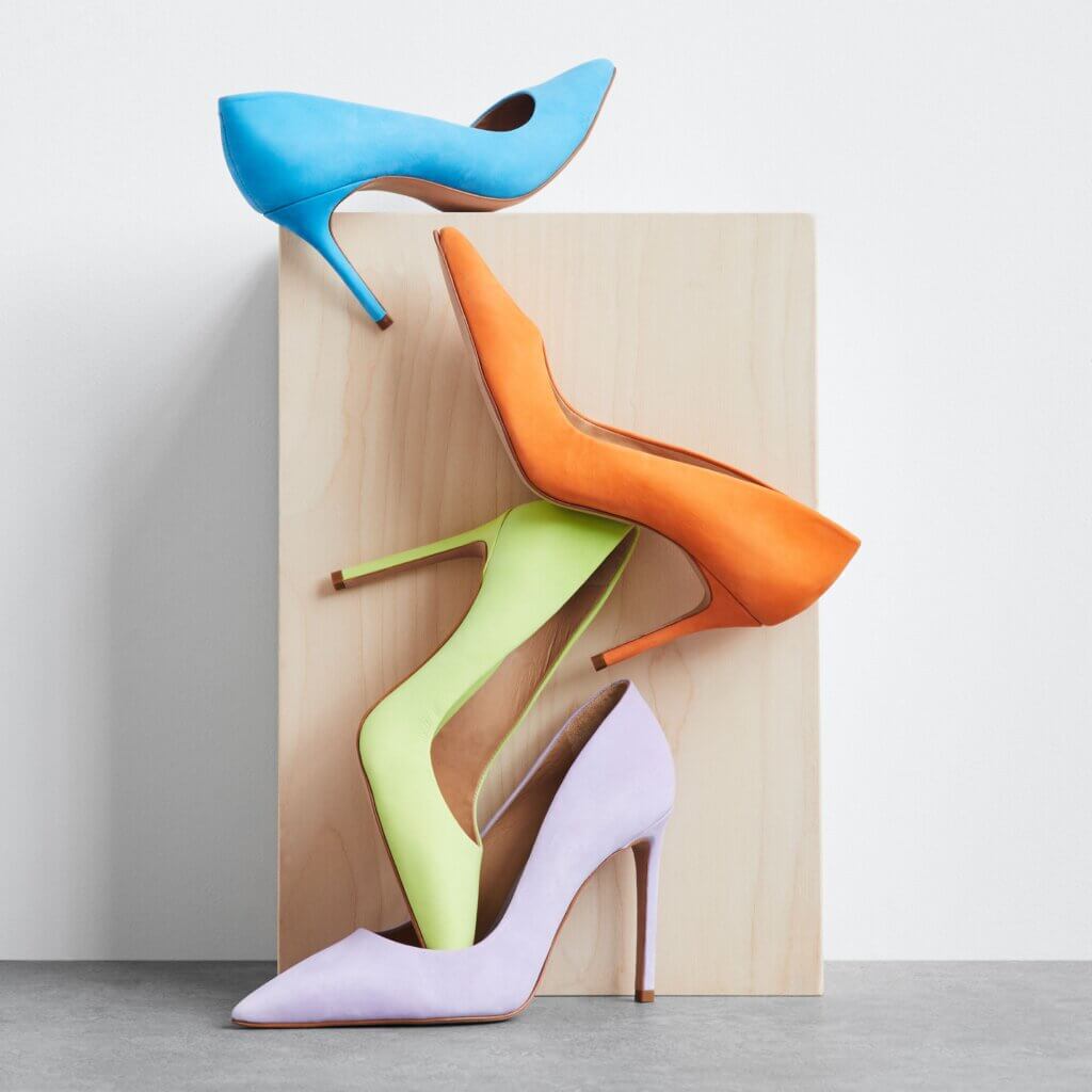 Stitch Fix women’s high heels in blue, orange, lime green and lavender in front of a wooden stand.