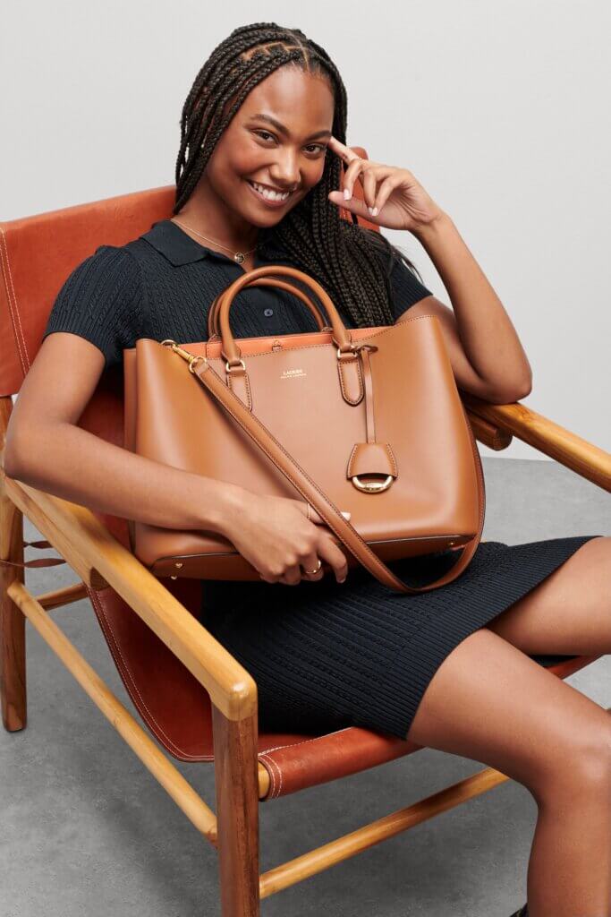 Stitch Fix model carrying women's brown leather satchel wearing black short-sleeve dress.