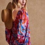 Stitch Fix model in women’s Americana aesthetic outfit featuring a straw hat hanging at the back of her neck and a multi-colored long-sleeve maxi dress.