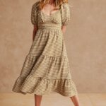 Stitch fix model wearing picnic outfit featuring khaki and white gingham tiered ruffle dress and white sandals.