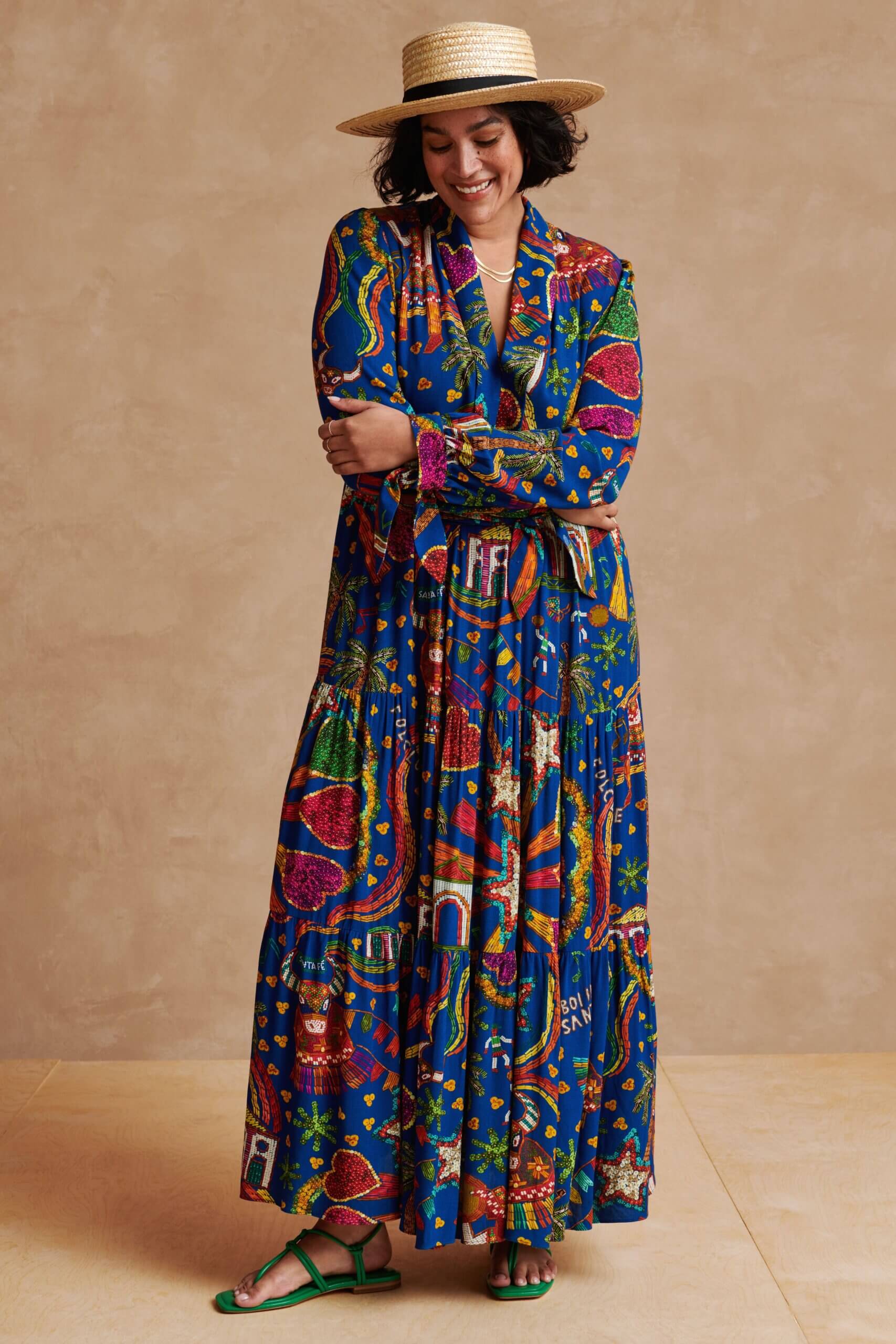 Stitch Fix model wearing women’s destination beach wedding attire with tropical maxi dress, green sandals and woven hat.
