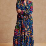 Stitch Fix model wearing picnic outfit featuring multi-colored abstract print maxi dress, tan wide-brim hat and green sandals.
