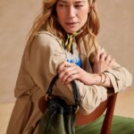 Stitch Fix model carrying women's bucket type of bag wearing trench jacket and pants.