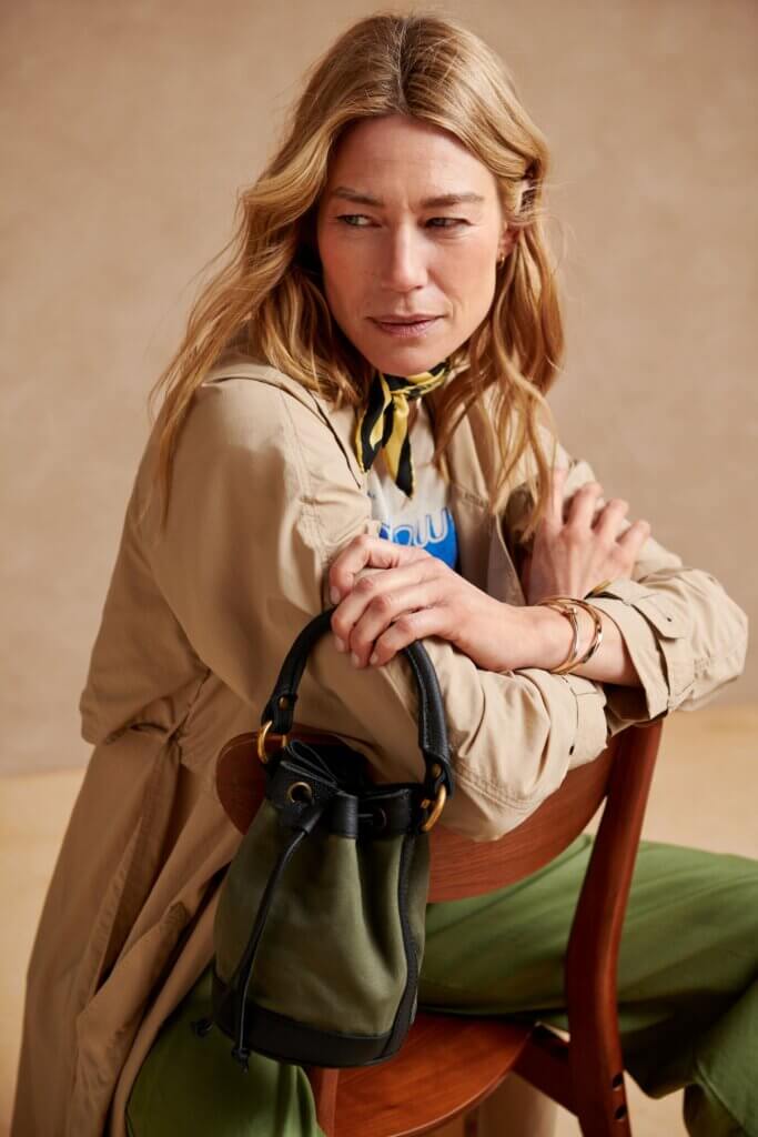 Stitch Fix model carrying women's bucket type of bag wearing trench jacket and pants.