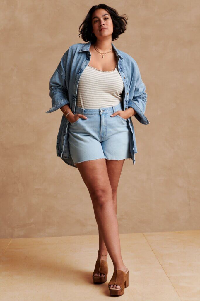 Stitch Fix model wearing women's 90s fashion outfit with jean shorts, striped T-shirt, denim shirt, layered jewelry and platforms.