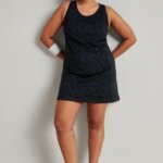 Stitch Fix women’s model wearing a tennis outfit including black active dress, white sneakers, wrist band and white visor.