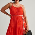Stitch Fix model wearing a red dress with white rope belt, with black bag and necklace accessories.