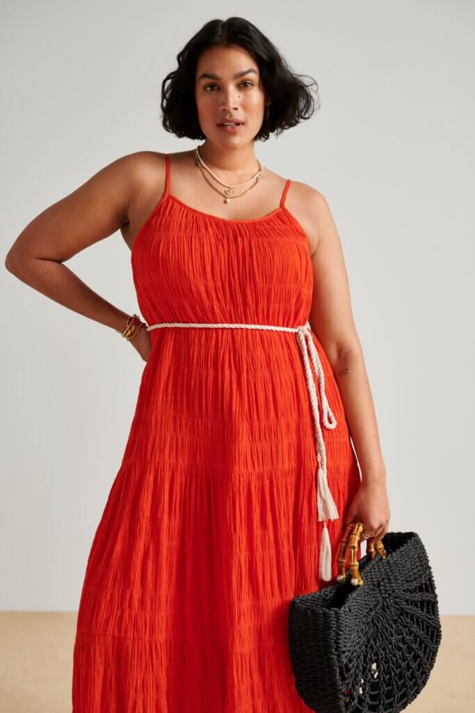 Stitch Fix model wearing a red dress with white rope belt, with black bag and necklace accessories.