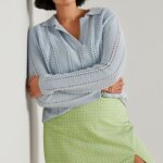 Stitch Fix model wearing women’s preppy style outfits featuring green plaid mini skirt and blue collared sweater.