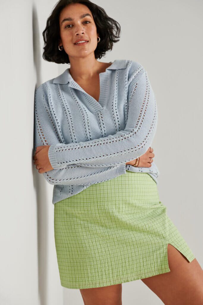 Stitch Fix model wearing women’s preppy style outfits featuring green plaid mini skirt and blue collared sweater.