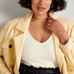 Stitch Fix model wearing women's edgy style outfit with white top, tan blazer and black leather shorts with tie waist.