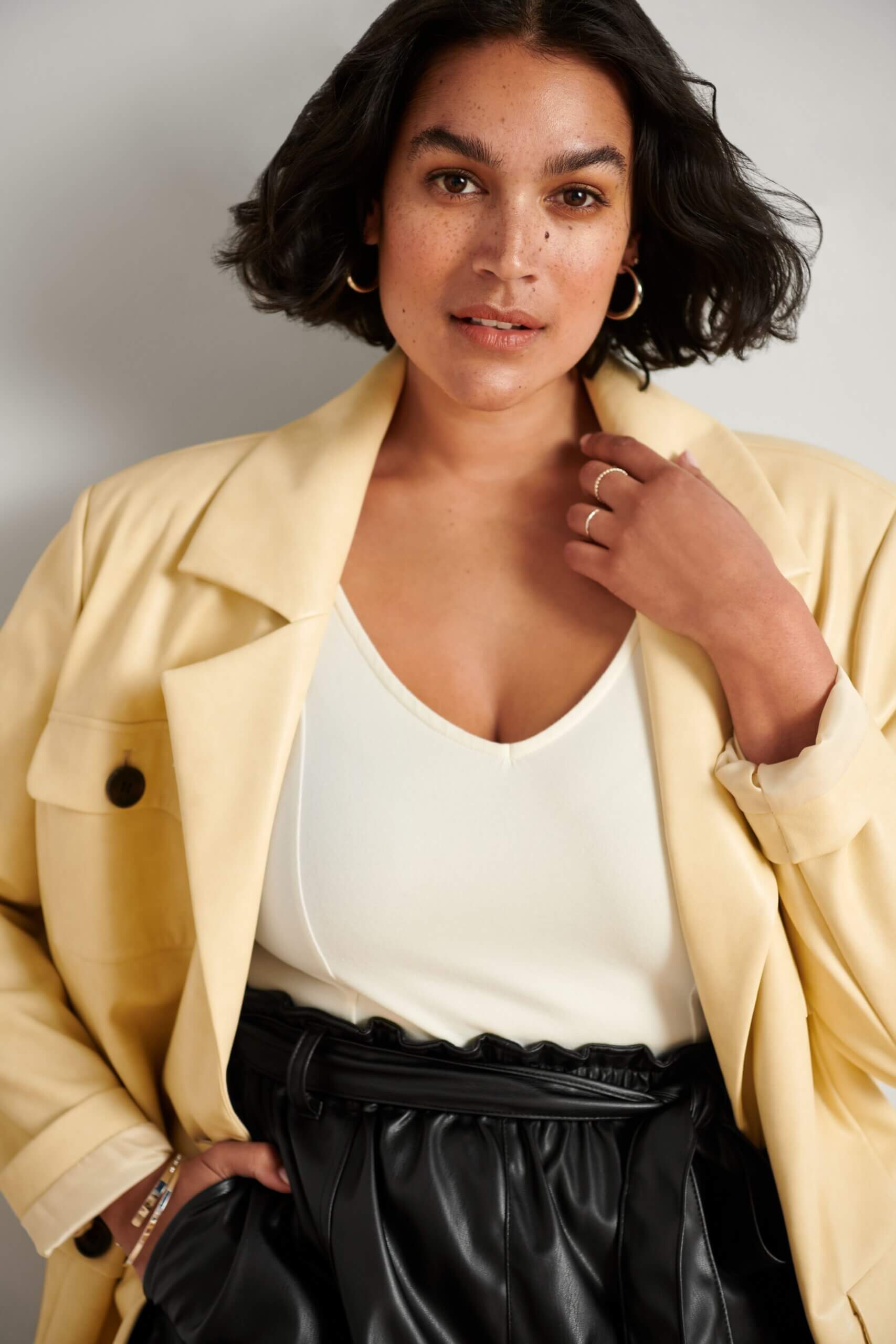 Stitch Fix model wearing women's edgy style outfit with white top, tan blazer and black leather shorts with tie waist.