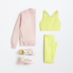 Stitch Fix women’s tennis outfit including a pink sweatshirt, yellow sports bra, yellow leggings and pink sneakers.