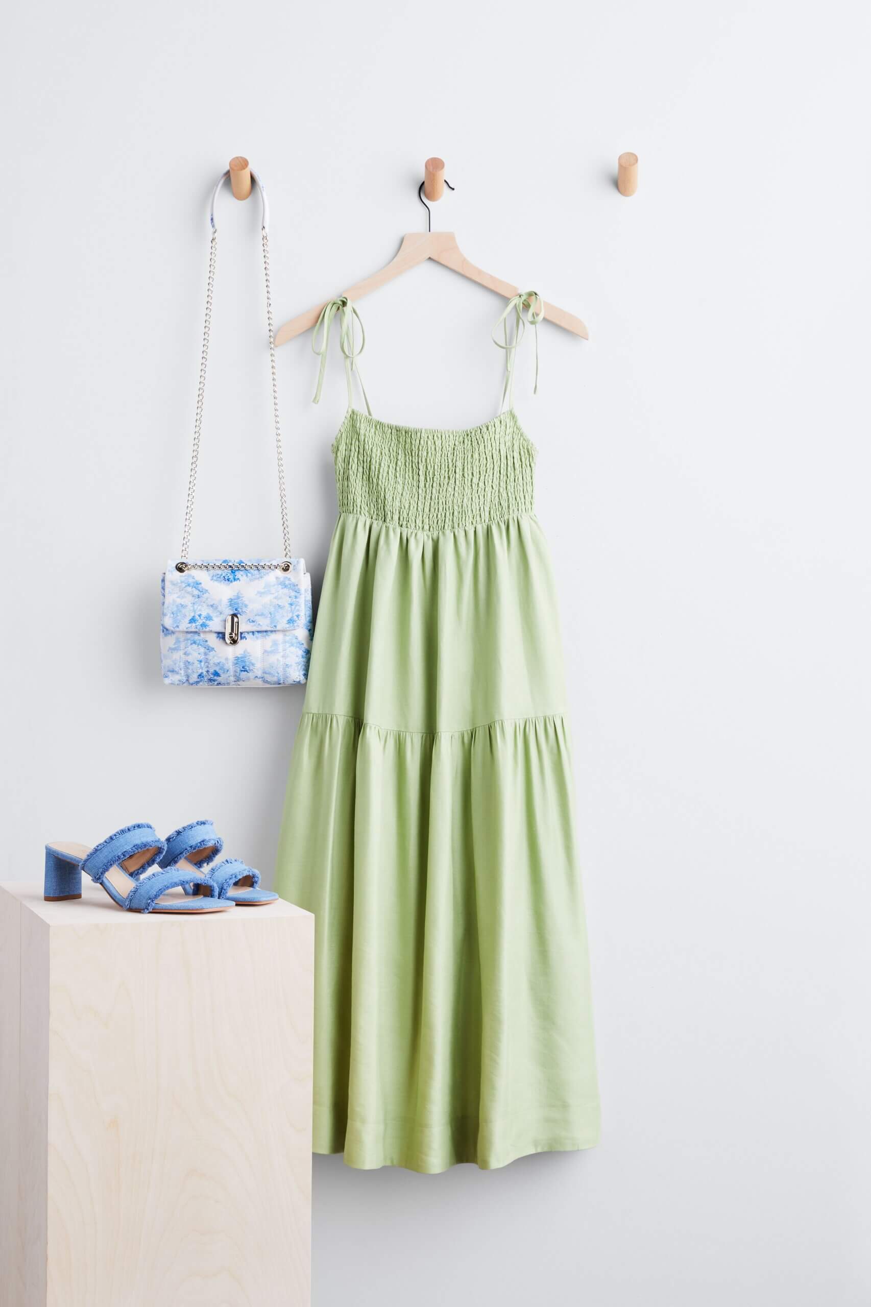 Stitch Fix women’s casual wedding beach attire with green tiered maxi dress hanging next to bag with chain strap and heels.