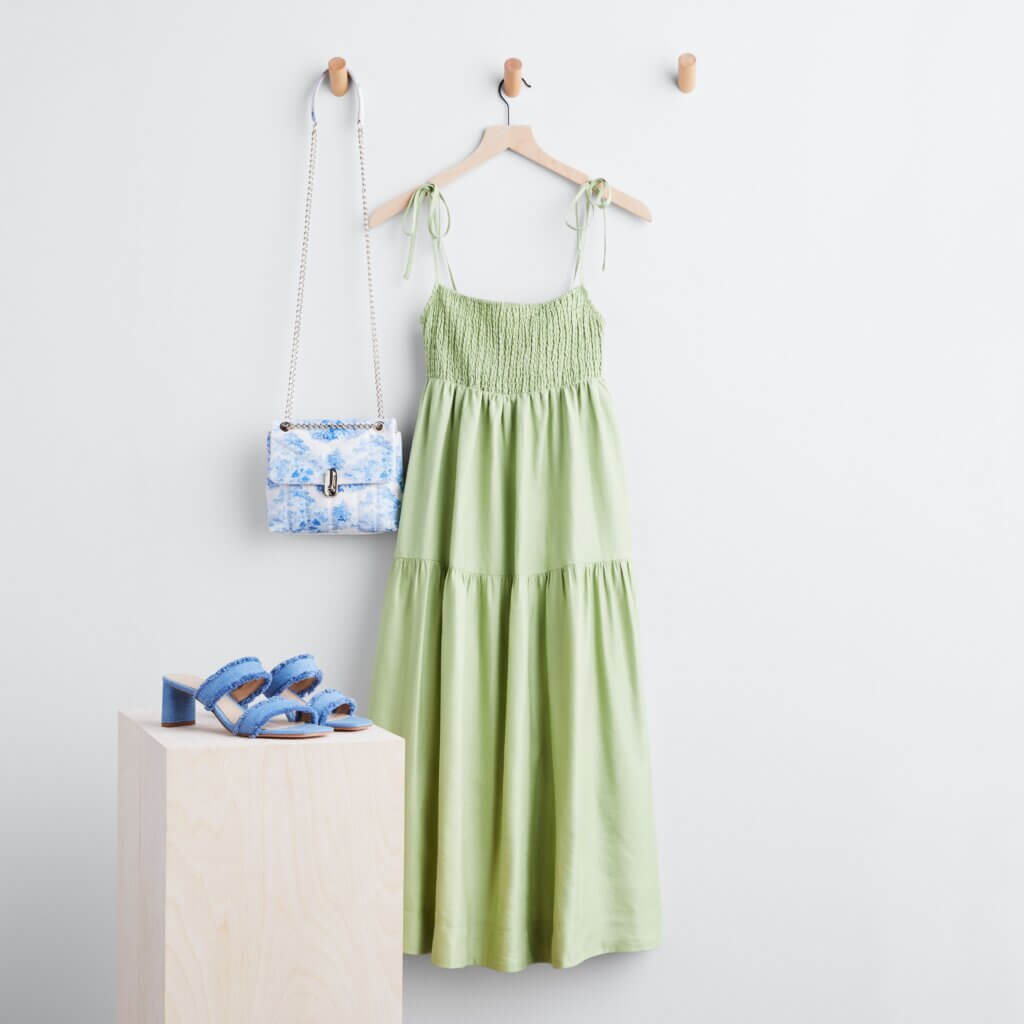 Stitch Fix Bridgerton inspired women’s outfit featuring green tiered maxi dress, blue sandals and white and blue purse.