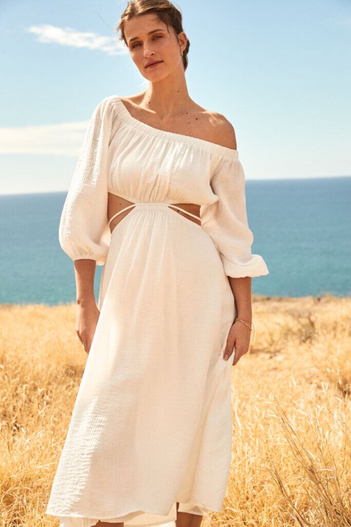 Stitch Fix model wearing women’s beach bridal wedding attire with white off-the-shoulder cut-out dress on the coast.