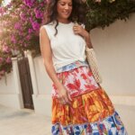 Stitch Fix women’s model wearing comfy road trip outfit with colorful tiered midi skirt, beige knot tank, tan crochet bag.