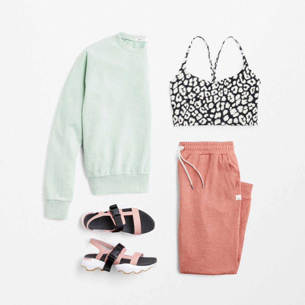 Stitch Fix women’s comfy road trip outfit with black and white animal print sports bra, mint pullover, pink joggers and sport sandals.