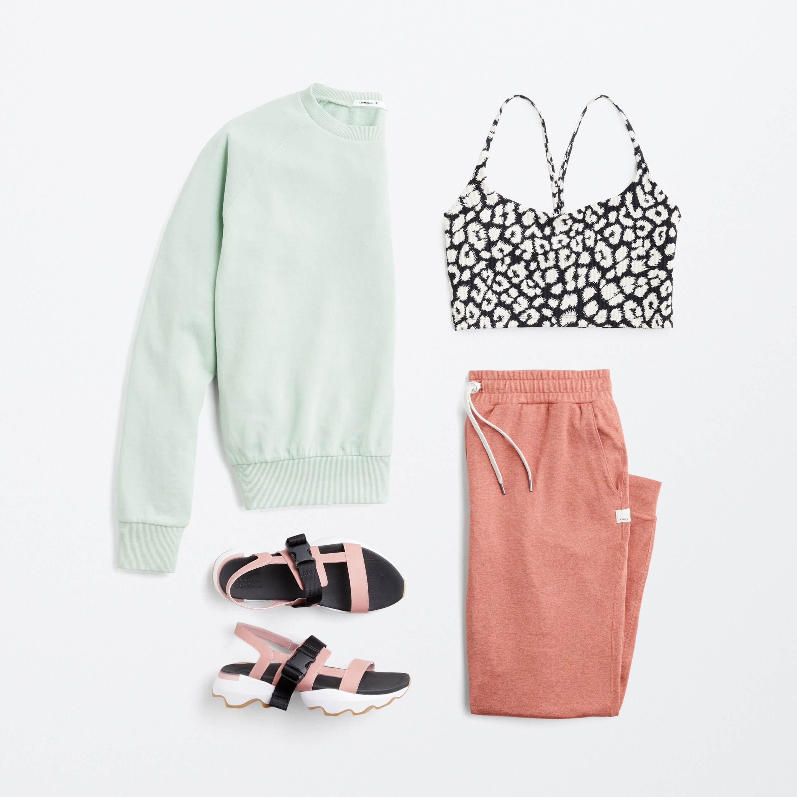 Stitch Fix women’s comfy road trip outfit with black and white animal print sports bra, mint pullover, pink joggers and sport sandals.