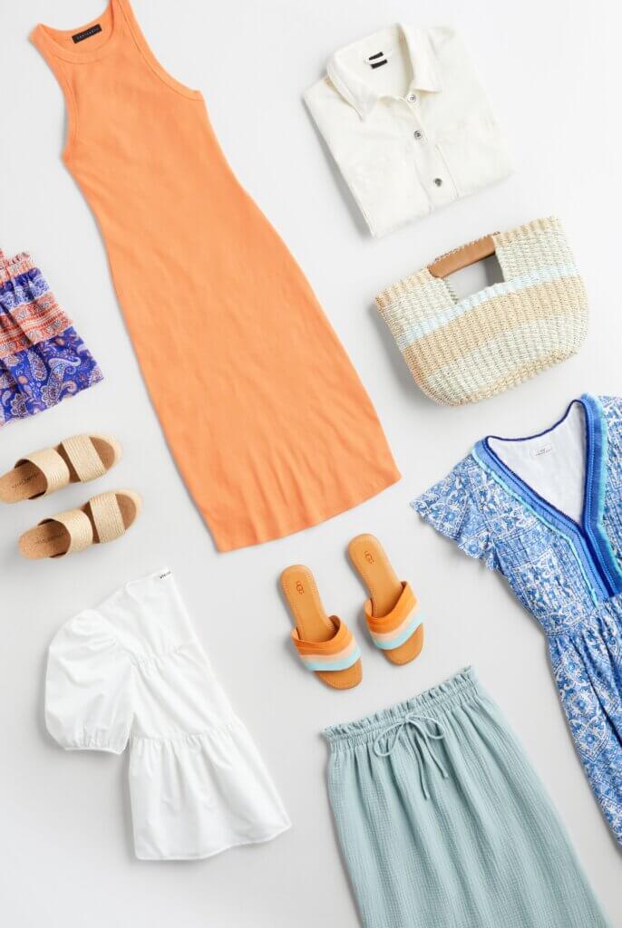 Stitch Fix women's picnic outfit featuring yellow blouse, green shorts, black and white tote hanging on rack and brown sandals on stool.