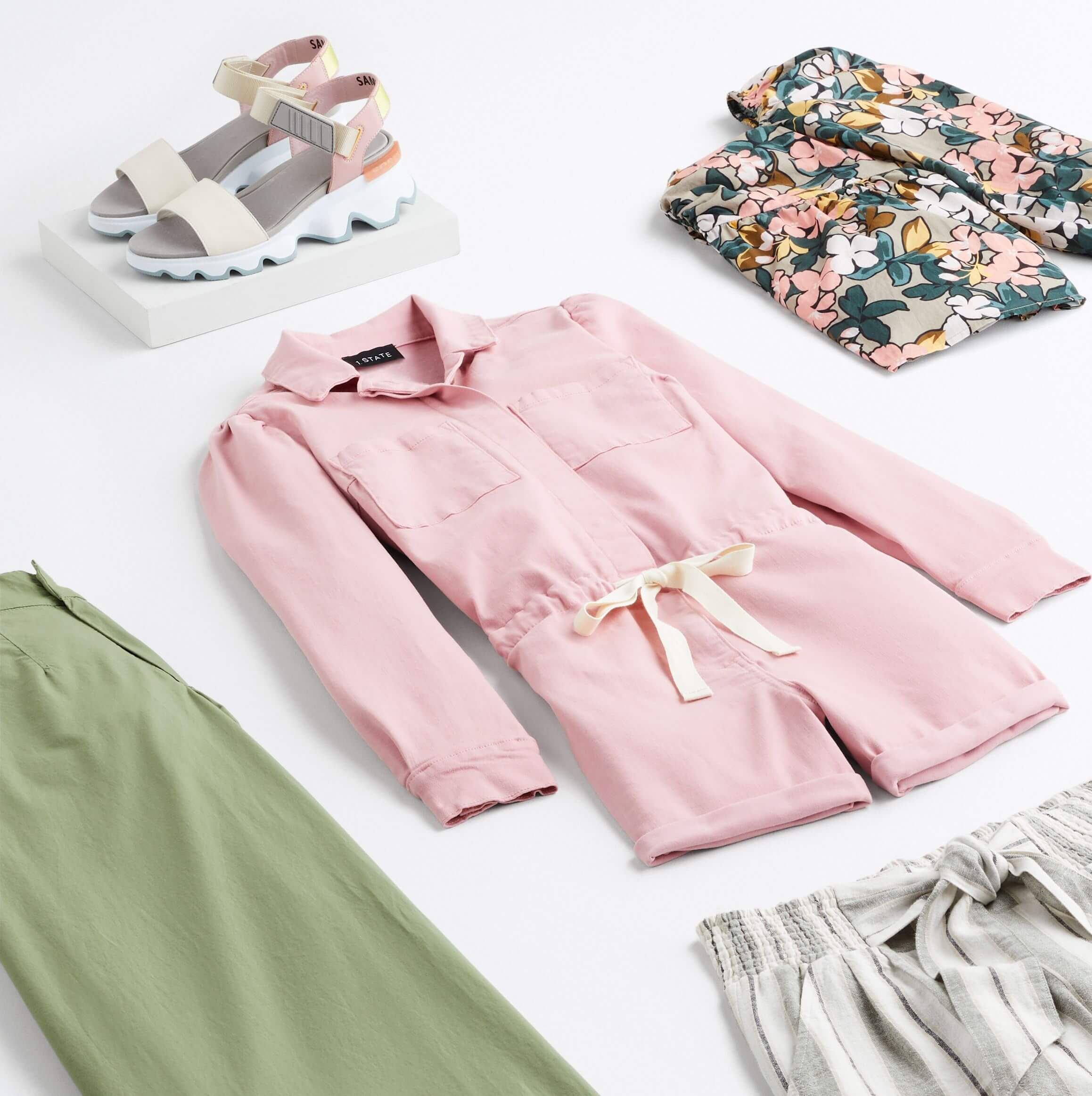 Stitch Fix women’s road trip outfit with pink romper, green pants, floral top, striped shorts and multicolored sandals.