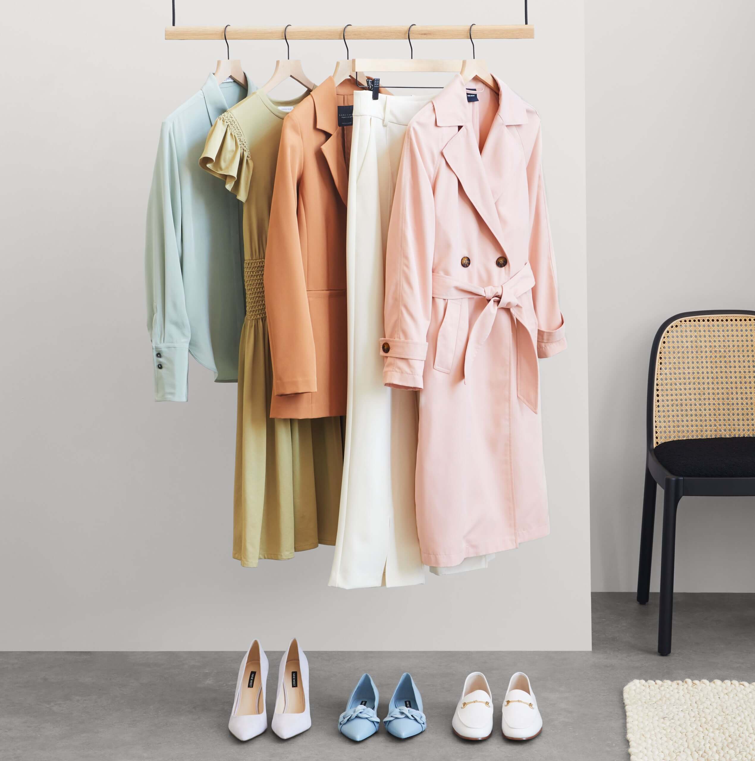 Stitch Fix women’s array of business formal attire with jackets, pants, dress and top on a rack next to shoes and chair.