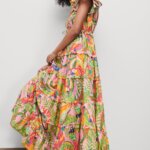 Stitch Fix model wearing women’s regencycore outfit featuring printed tiered maxi dress, brown sandals and green and gold statement earrings.
