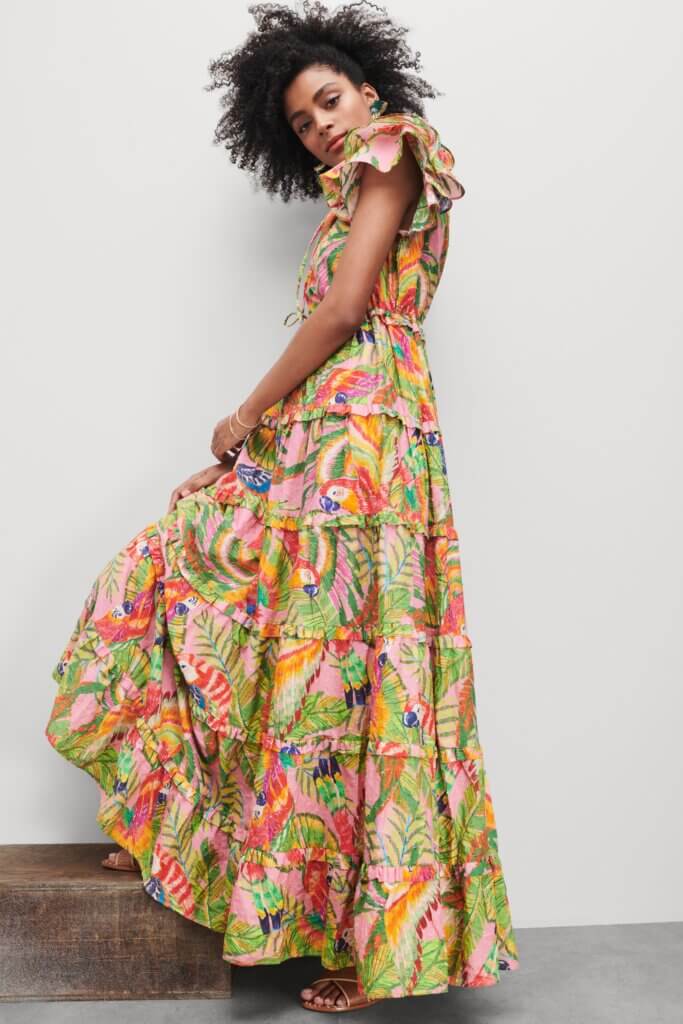 Stitch Fix model wearing women’s regencycore outfit featuring printed tiered maxi dress, brown sandals and green and gold statement earrings.