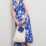 Stitch Fix women’s model wearing floral accessorized navy blue dress for a wedding with purse, watch, necklace and earrings.