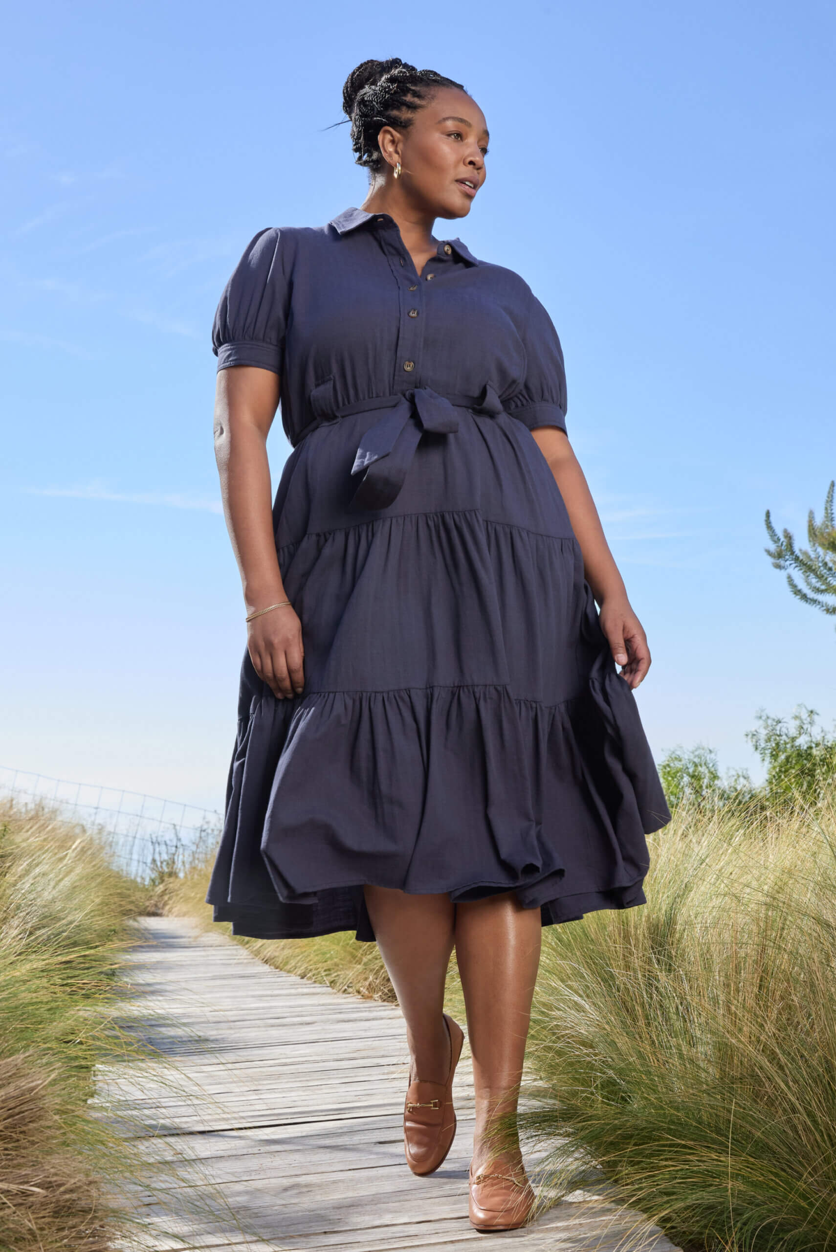  A woman in a short-sleeved, dusky blue tiered shirtdress.