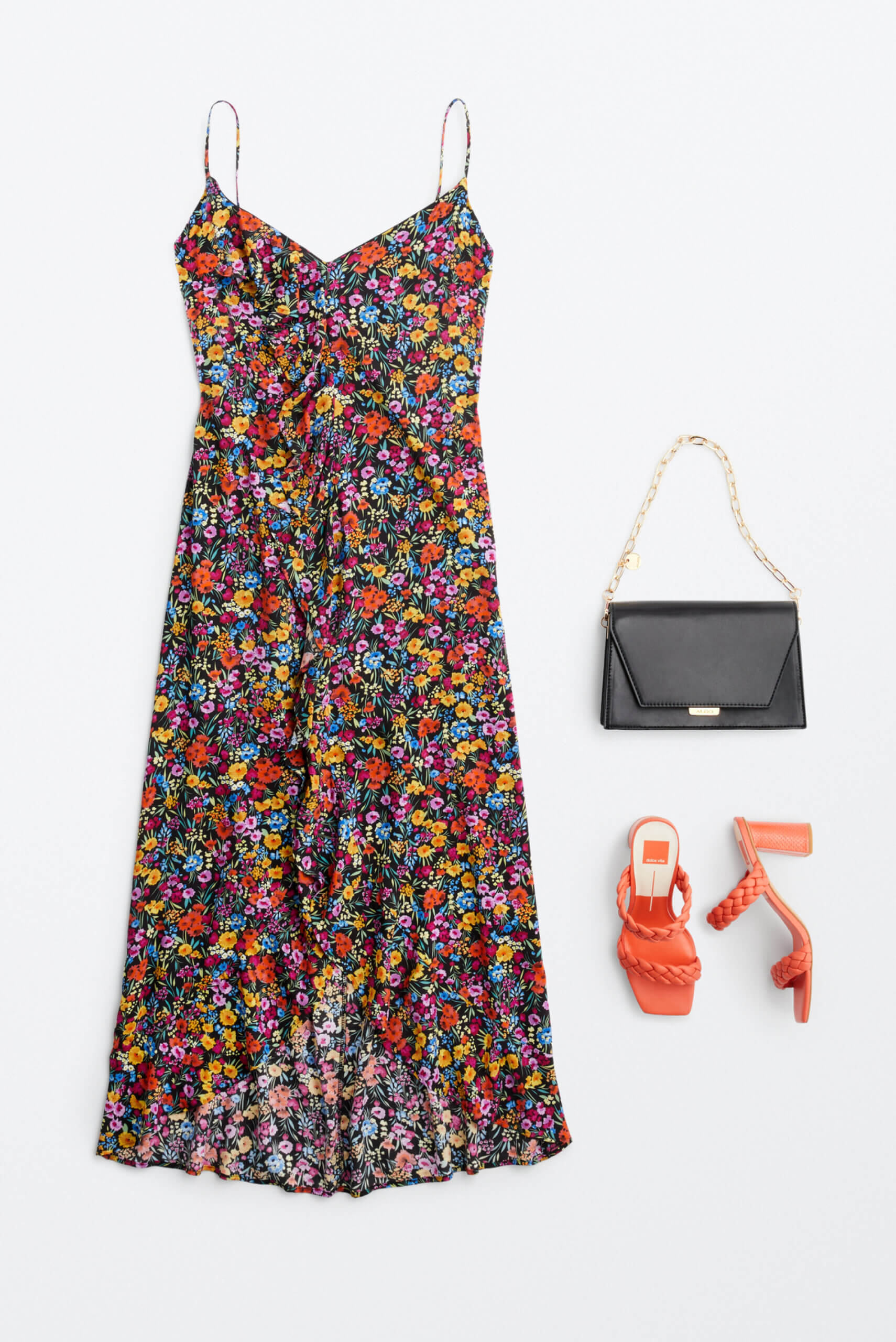 Alt text: A long floral slip dress, a black clutch purse and orange heels arranged together for outfit inspiration. 